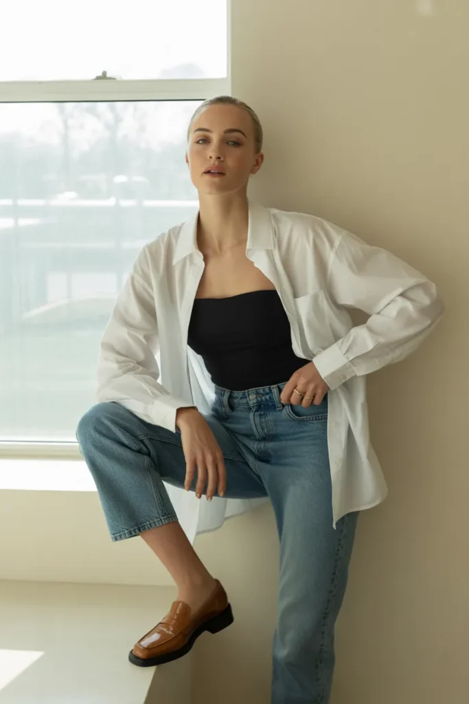 White button-down shirt styled open over black bodysuit and cropped jeans